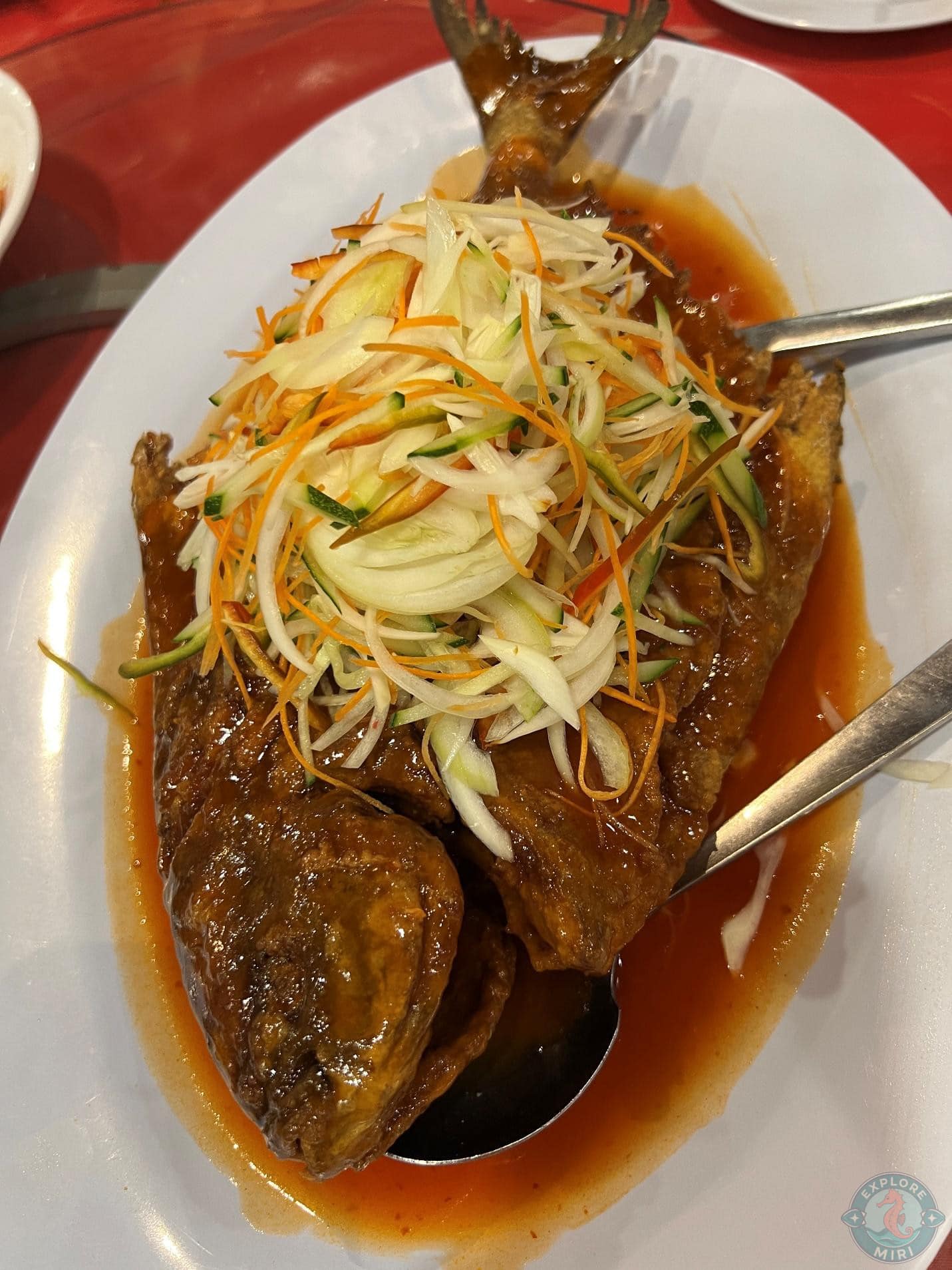fried fish covered in a sweet and spicy sauce and served with a bed of veggies